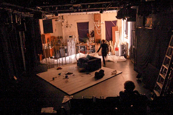 A grand piano and scattered props occupy a stage with its backstage structure exposed.