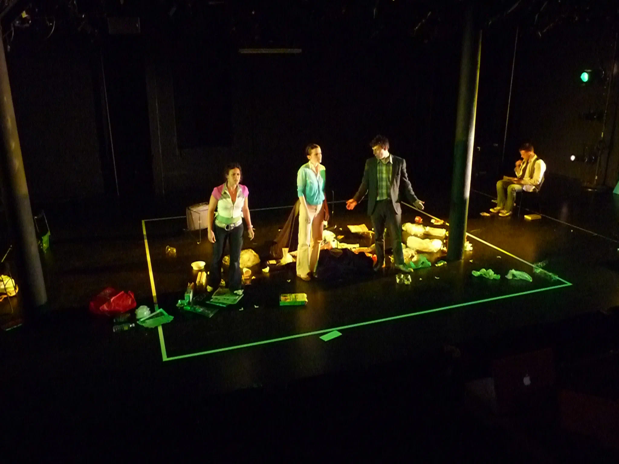 An ensemble stands within a bright green rectangular floor design onstage.