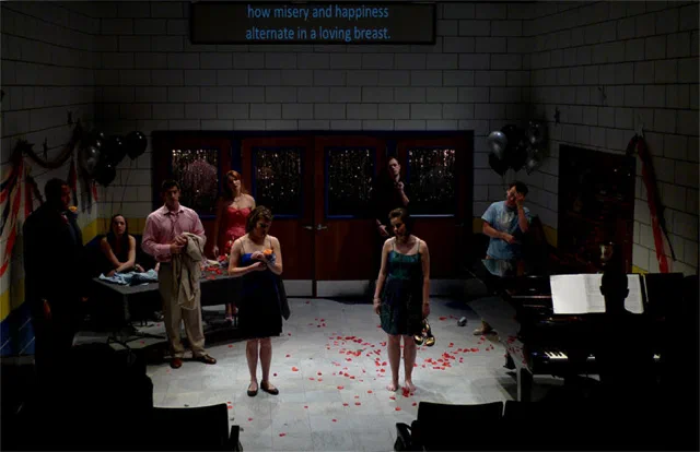 An ensemble gathers on a festive set scattered with red flower petals.