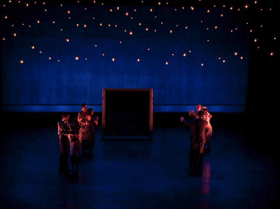 Pairs of performers dance across a blue stage framed by glowing rectangles.