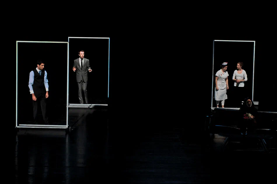 Performers stand in separate glowing frames while a pianist sits at the side of the stage.