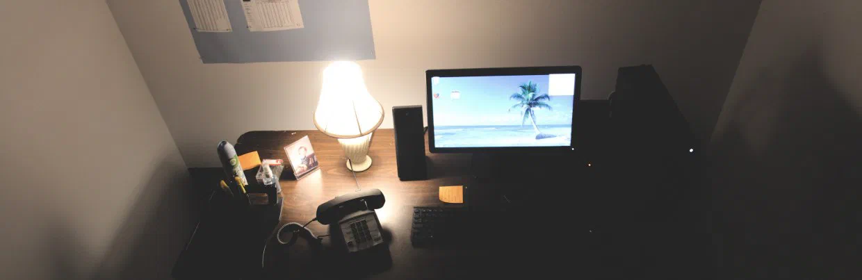 A telephone, lamp, computer, speakers, and office supplies fill the Temping desk.
