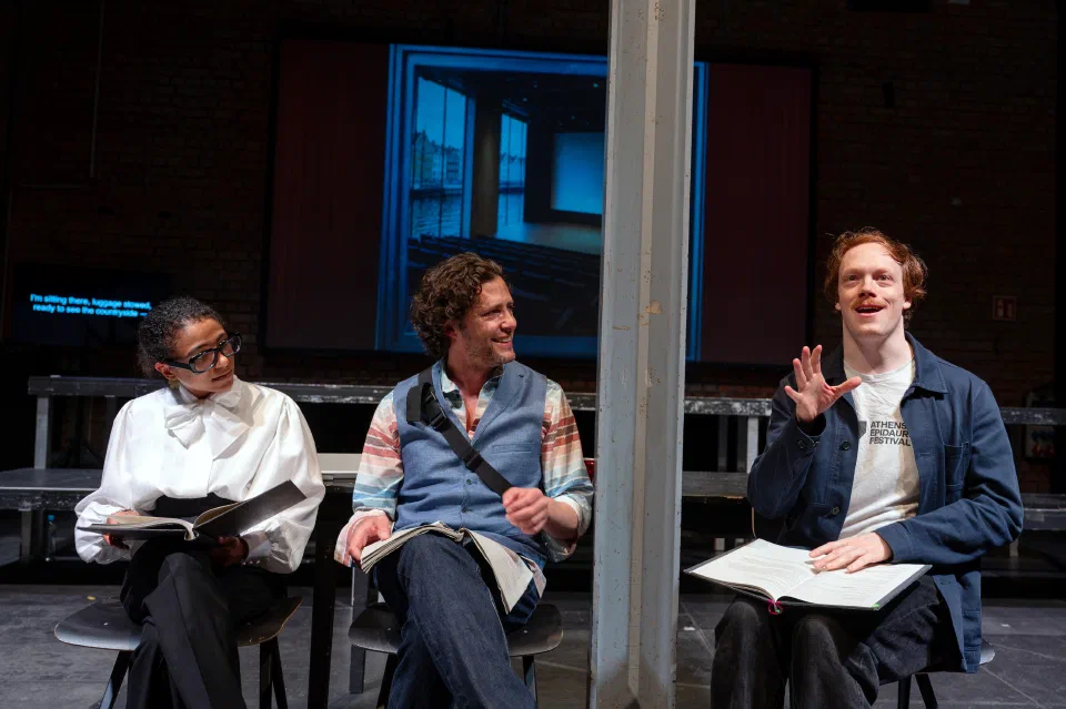 Three performers sit together behind clear scenic panels during the Hamlet.ai workshop.