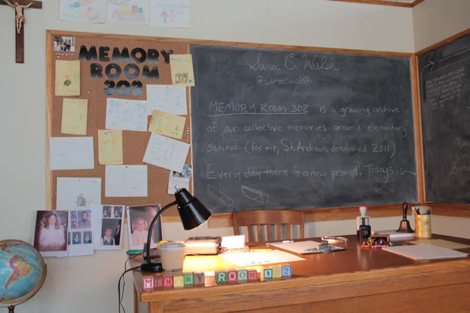 A desk installation combines a chalkboard, notes, lamp, and blocks spelling Room 302.