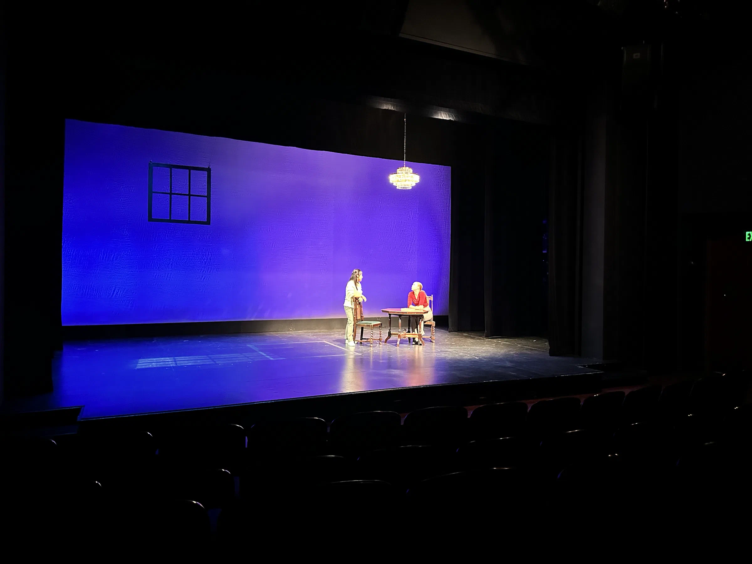 Performers occupy a sparse stage washed in deep blue light.