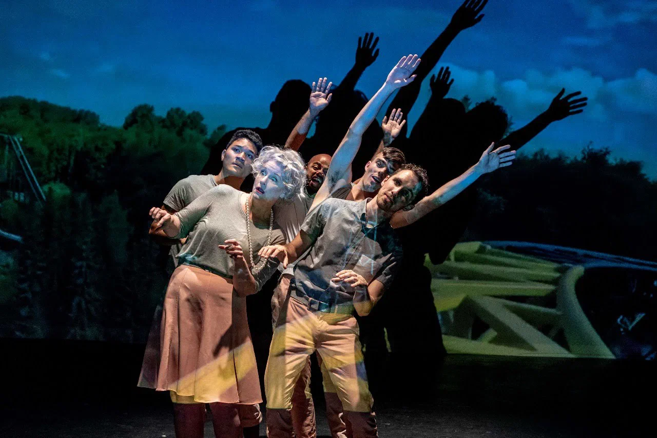 An ensemble reaches upward together against a projected landscape.